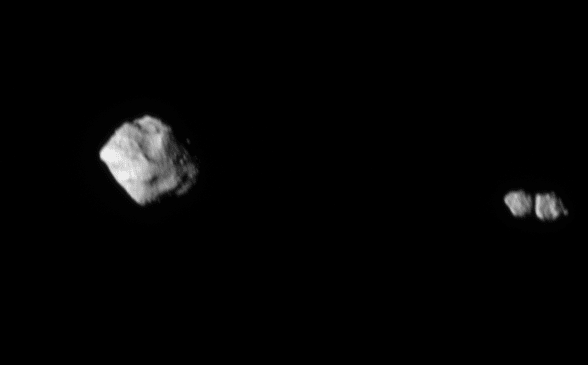 One large gray asteroid sits on the left side of a black field, while two smaller gray asteroids nearly touching each other sit on the right.